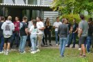 Studierende und Lehrkräfte stehen vor der Aula im Außenbereich und unterhalten sich