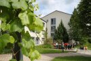 Studierende sitzen am Tisch vom Grillplatz vor dem Wohnheim