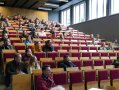Interessierte sitzen in der Aula und hören dem Schulleiter zu