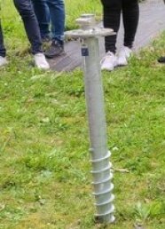 Ein 1 Meter lange Schraube steckt im Gras